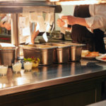 Food orders on the kitchen table in the restaurant, chief reading orders and cooking in professional restaurant kitchen